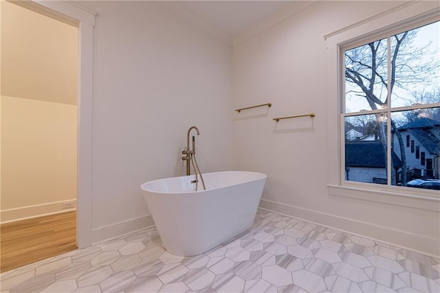 bathroom featuring a soaking tub, baseboards, and crown molding