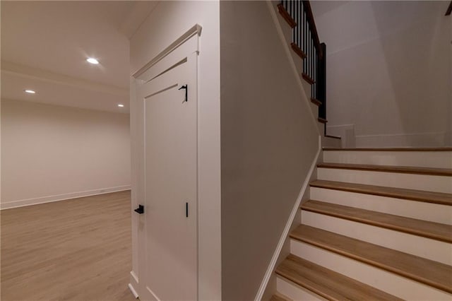 stairs with baseboards, wood finished floors, and recessed lighting