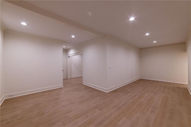 below grade area featuring light wood-type flooring, crown molding, and baseboards