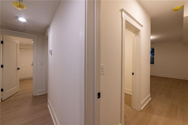 corridor with light wood-style flooring and baseboards