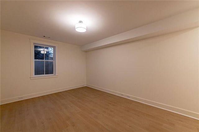 empty room with baseboards, visible vents, and light wood finished floors