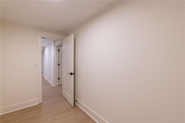 hall with light wood-style flooring and baseboards