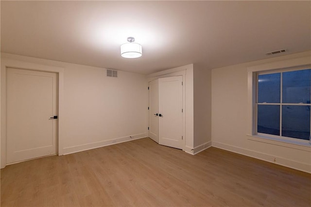 unfurnished room featuring light wood finished floors, visible vents, and baseboards