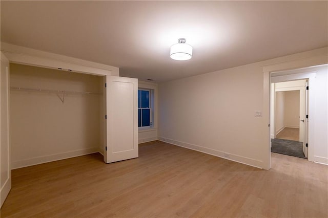 unfurnished bedroom featuring light wood-type flooring, baseboards, and a closet