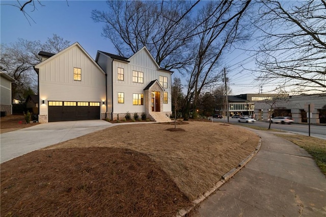 modern farmhouse style home featuring a garage, driveway, brick siding, and board and batten siding