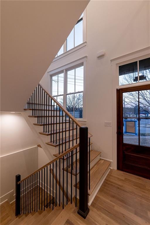 staircase with a towering ceiling and wood finished floors