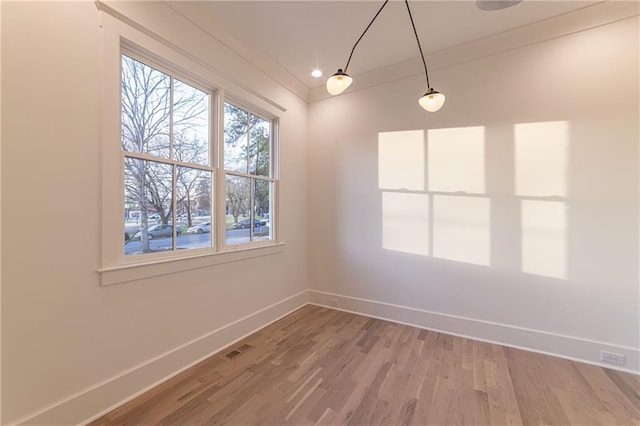 unfurnished room featuring light wood-style floors, visible vents, and baseboards