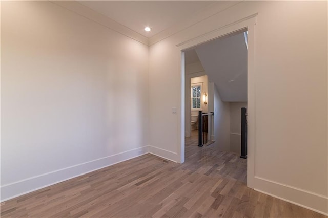 spare room with crown molding, baseboards, and wood finished floors