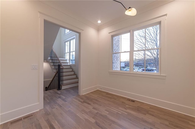 spare room with stairway, wood finished floors, visible vents, and baseboards