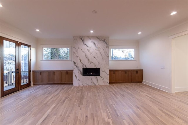 unfurnished living room featuring a healthy amount of sunlight, light wood finished floors, a premium fireplace, and recessed lighting