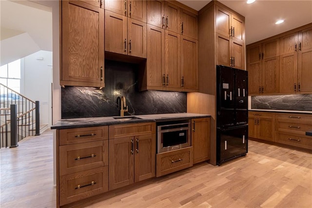 kitchen with double oven, light wood-style floors, a sink, and brown cabinets