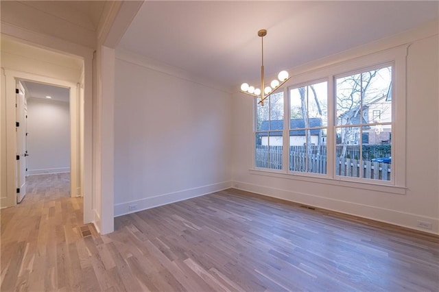 unfurnished dining area featuring a chandelier, visible vents, baseboards, ornamental molding, and light wood finished floors