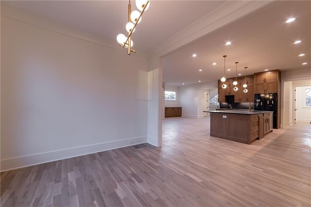 kitchen with recessed lighting, baseboards, open floor plan, light wood finished floors, and a center island with sink