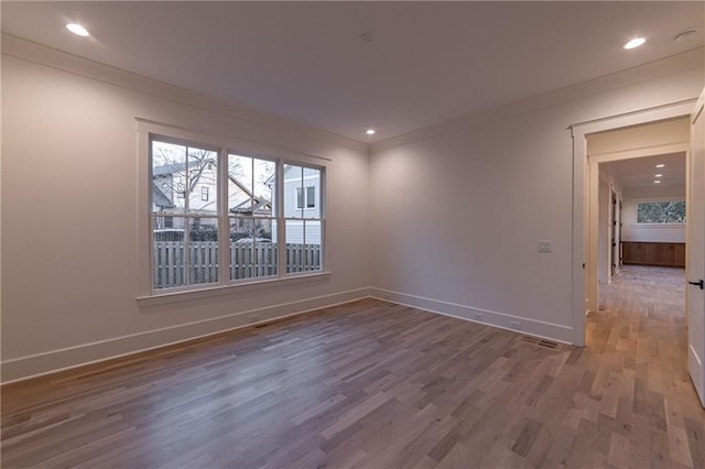 empty room with ornamental molding, recessed lighting, wood finished floors, and baseboards