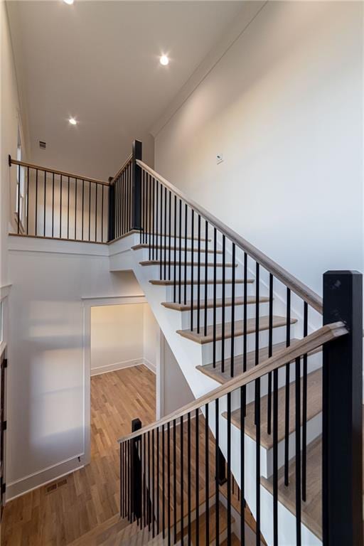 stairs with wood finished floors and recessed lighting