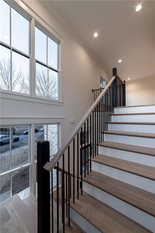 stairs with wood finished floors and recessed lighting