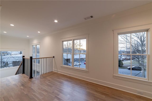 empty room with baseboards, visible vents, wood finished floors, crown molding, and recessed lighting