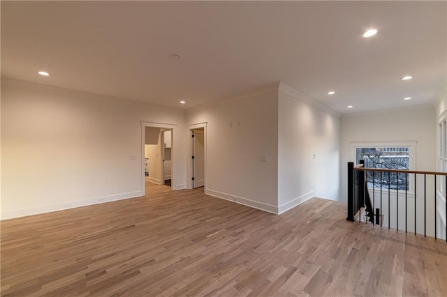 spare room featuring light wood-style floors, baseboards, crown molding, and recessed lighting