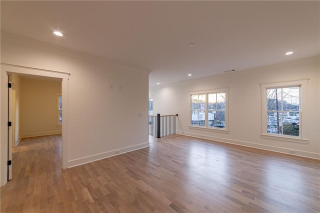 empty room with ornamental molding, recessed lighting, wood finished floors, and baseboards