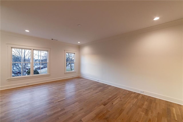 spare room with recessed lighting, crown molding, baseboards, and wood finished floors