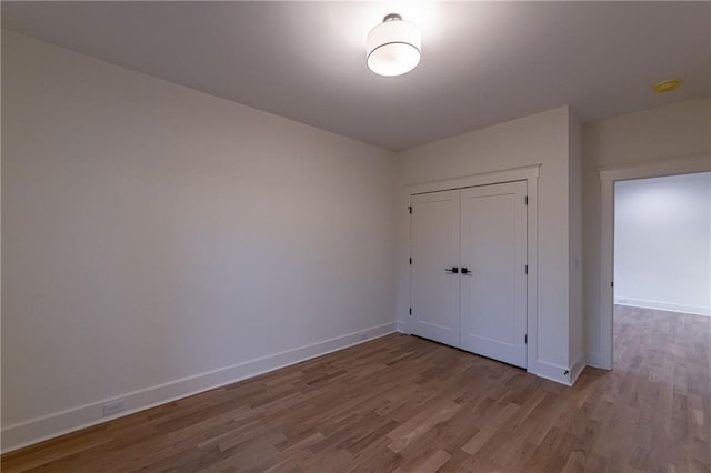 unfurnished bedroom with a closet, baseboards, and wood finished floors