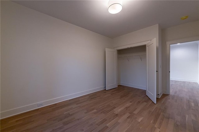 unfurnished bedroom featuring a closet, wood finished floors, and baseboards