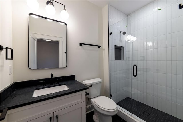 bathroom with vanity, a shower stall, and toilet