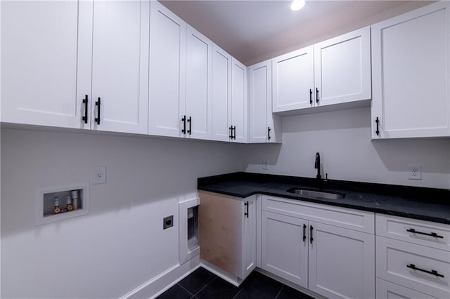 laundry room featuring hookup for an electric dryer, dark tile patterned flooring, washer hookup, a sink, and cabinet space