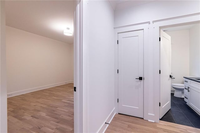 corridor with light wood-type flooring and baseboards