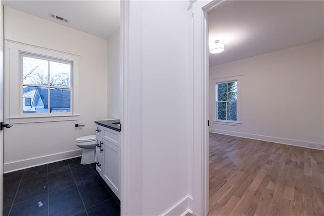 bathroom featuring toilet, vanity, a wealth of natural light, and baseboards