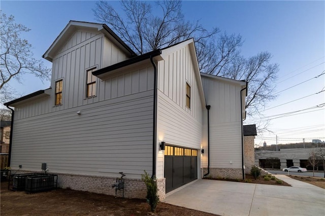 view of home's exterior with a garage, central AC, board and batten siding, and concrete driveway