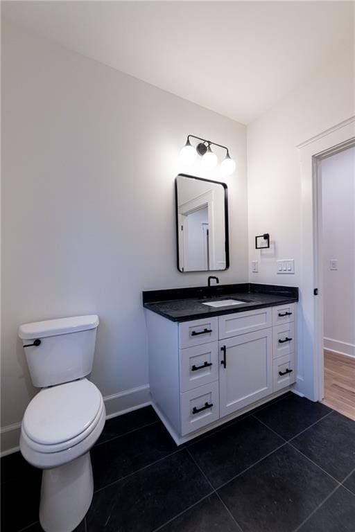 half bath featuring tile patterned flooring, baseboards, vanity, and toilet