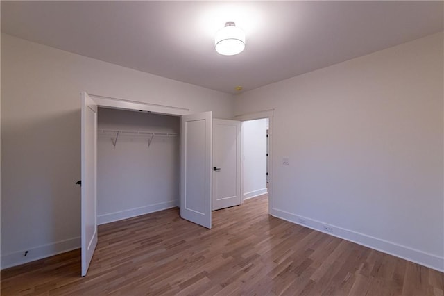 unfurnished bedroom featuring a closet, wood finished floors, and baseboards