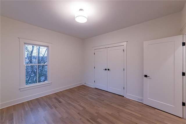 unfurnished bedroom featuring a closet, baseboards, and wood finished floors