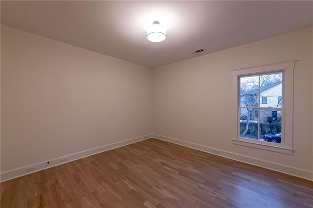 spare room with visible vents, baseboards, and wood finished floors