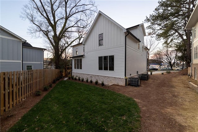 rear view of house with a yard, board and batten siding, fence, and central air condition unit