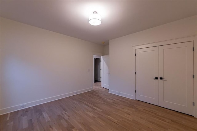 unfurnished bedroom with a closet, wood finished floors, and baseboards