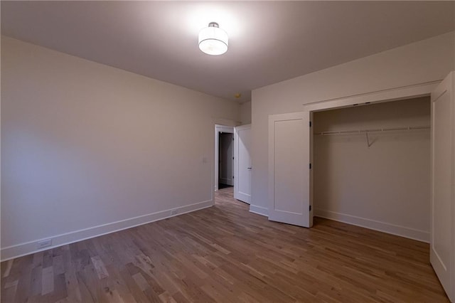 unfurnished bedroom featuring a closet, baseboards, and wood finished floors