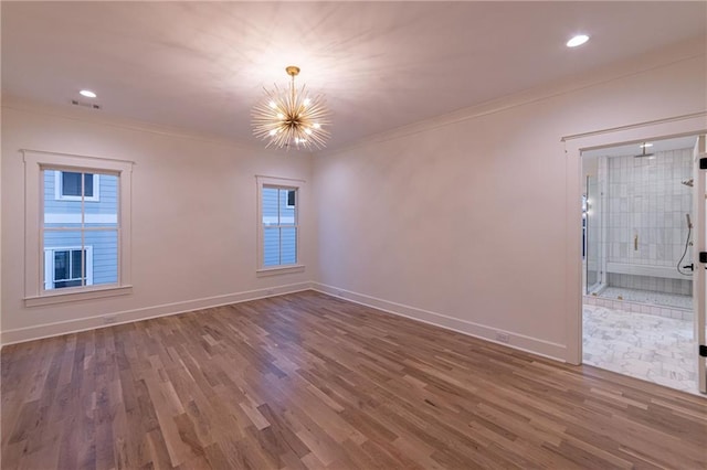 empty room featuring baseboards, visible vents, ornamental molding, wood finished floors, and a chandelier