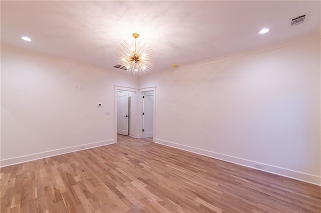 spare room with a chandelier, visible vents, baseboards, light wood finished floors, and crown molding