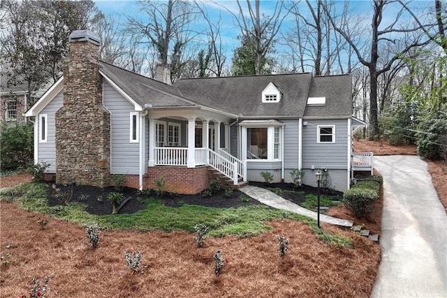 view of front of home featuring a porch, roof with shingles, and a chimney
