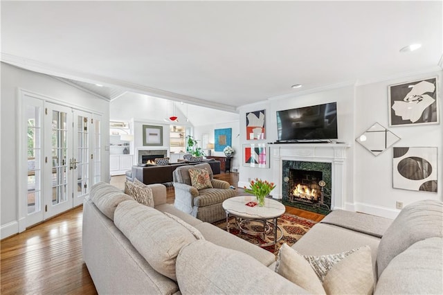 living room featuring french doors, wood finished floors, a fireplace, and ornamental molding