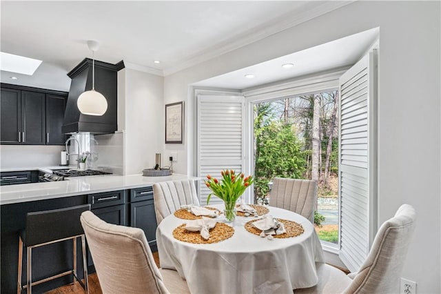 dining space featuring crown molding, a skylight, wood finished floors, and recessed lighting