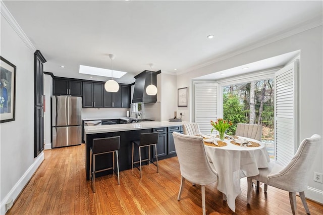 kitchen with a peninsula, stainless steel refrigerator, ornamental molding, light countertops, and custom range hood