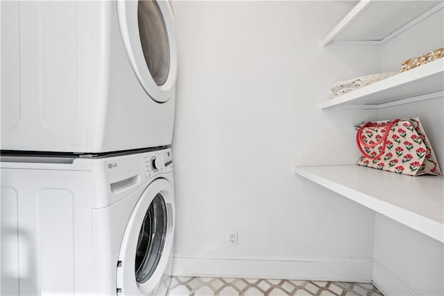 laundry area with baseboards, stacked washer and dryer, and laundry area