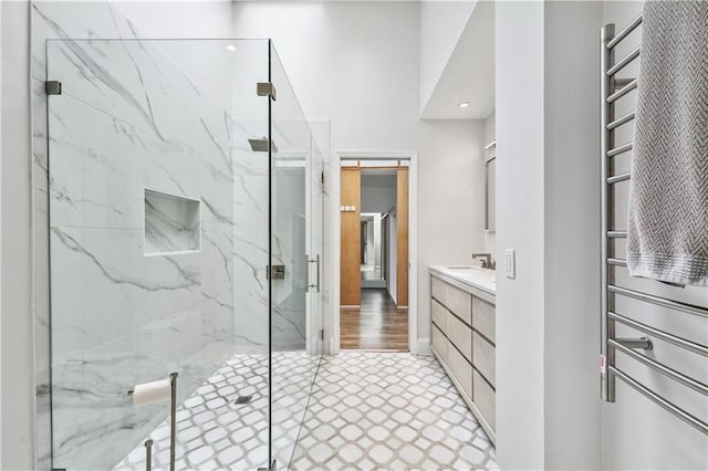 bathroom with a marble finish shower, vanity, and recessed lighting