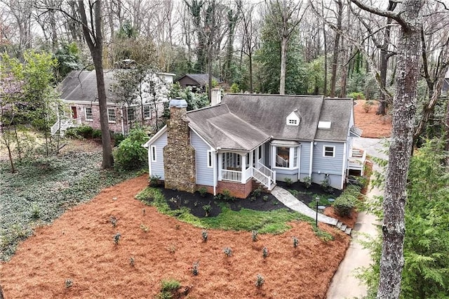 view of front of house with a shingled roof and a chimney