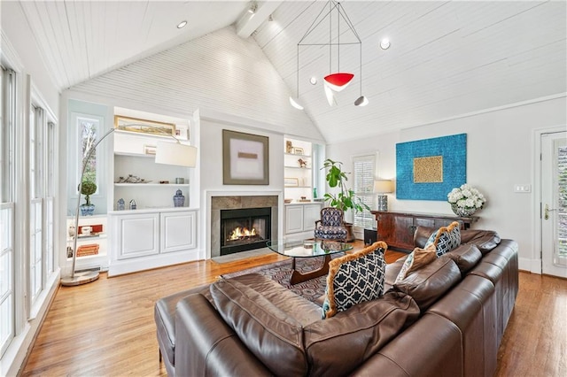 living room featuring built in features, lofted ceiling, a healthy amount of sunlight, and wood finished floors