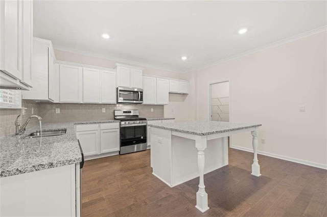 kitchen featuring sink, light stone counters, a kitchen island, stainless steel appliances, and white cabinets