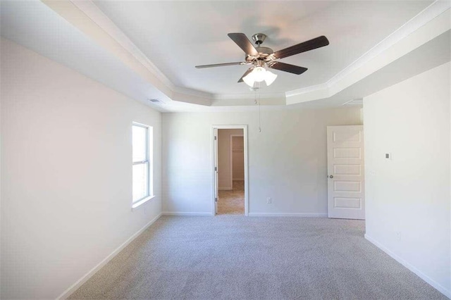 carpeted spare room with a tray ceiling, ornamental molding, and ceiling fan